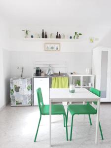 a kitchen with a table and two green chairs at Rosso di Sera Loft in Menfi