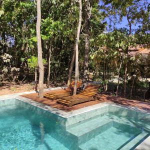 a swimming pool with two benches next to a swimming pool at TEMPLÁRIOS ECOVILLA Pousada in Pirenópolis