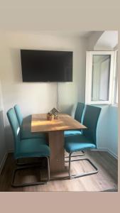 a dining room table with blue chairs and a television at Apartments Nina in Koper