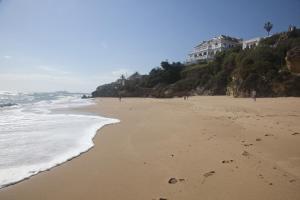 a beach with a building on a hill next to the ocean at Hostal Mar de Frente in Los Caños de Meca