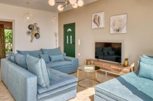 a living room with two blue couches and a tv at Roxa seaview apartment in Agios Leon
