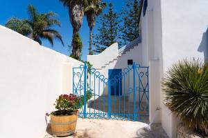 a white house with a blue gate and a potted plant at Villa Le Charme Marin - Noto, Marzamemi, San Lorenzo in San Lorenzo