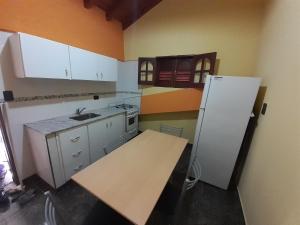 a kitchen with a white refrigerator and a table at Hospedate en nuestro hogar y disfruta unas lindas vacaciones en Termas de Rio Hondo in Termas de Río Hondo