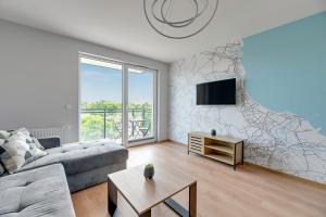 a living room with a couch and a tv at Apartament Letnica Białe Piaski by TriApart in Gdańsk