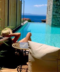 a woman laying on a chair next to a swimming pool at Petrichor in Kalamata