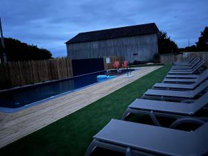 a swimming pool with lounge chairs and a building at La Buissonnière Lodges in Chisseaux