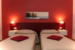 two beds in a room with red walls and lamps at Casa Amato_2_Regina Giovanna in Naples