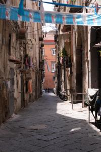 an alley in an old building with a person sitting on a bench at Casa Amato_2_Regina Giovanna in Naples