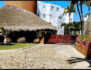 un bâtiment avec un toit de paille, des escaliers et des fleurs dans l'établissement Acapulco Diamante Varadero D001, à Acapulco