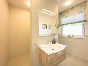 a white bathroom with a sink and a window at Appartements "Zum Leuchtturm" Hafen Rankwitz Insel Usedom in Rankwitz
