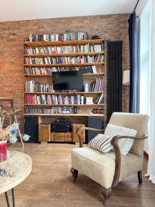 a living room with a chair and a tv at Lofts Cracow Apartments - City Center in Krakow