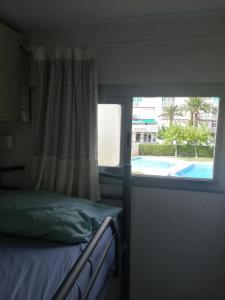 a bedroom with a bed and a window with a view of a pool at Edificio Salou Beach, la Pineda, Vilaseca in La Pineda