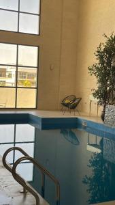 einen Pool mit einem Tisch und einer Bank in einem Gebäude in der Unterkunft شالية مارينا مرباط in Mirbāţ