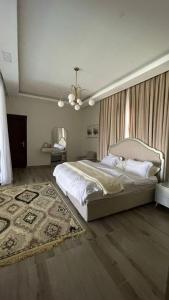 a bedroom with a large white bed and a rug at شالية مارينا مرباط in Mirbāţ