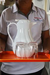 a woman holding a tray with a pitcher and wine glasses at Hotel Residencial Panamericano in David +30 photos