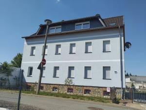 un grand bâtiment blanc sur le côté d'une rue dans l'établissement Gästewohnung OC, à Oschersleben
