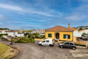 two cars parked in front of a yellow house at Livramento Residence in Livramento