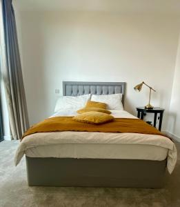 a bedroom with a large bed with orange sheets and pillows at Stunning & Luxury Flat in Sutton