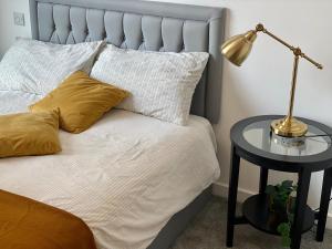 a bed with yellow pillows and a lamp on a table at Stunning & Luxury Flat in Sutton