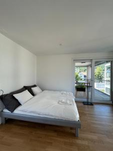 ein weißes Schlafzimmer mit einem Bett und einem Tisch in der Unterkunft The R Apartment Passwang, KLIMA, NEU, Balkon, Parking in Balsthal