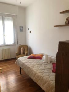 a bedroom with a bed and a chair and a window at Annarosa in Sarzana