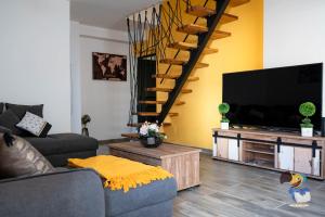 sala de estar con sofá y TV de pantalla plana en L'intemporelle - Piscine et Spa, en Le Tampon