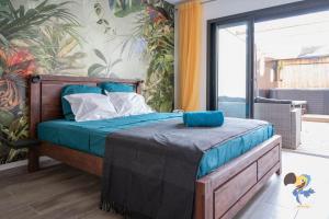 Schlafzimmer mit einem Bett mit blauer Bettwäsche und einem Balkon in der Unterkunft L'intemporelle - Piscine et Spa in Le Tampon