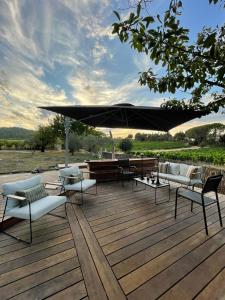 a wooden deck with chairs and a large umbrella at La Belugue in Beaumont-de-Pertuis