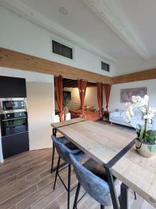 Il dispose d'une cuisine et d'un salon avec une table et des chaises en bois. dans l'établissement Appartement cosy & piscine privée - Le Strelitzia, à Vergèze