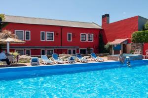 a swimming pool with chairs and a red building at Hosteria Casagrande in Tandil