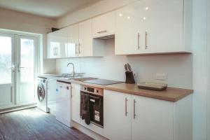 cocina con armarios blancos, fregadero y lavavajillas en Central Breaks - split level, spacious getaway, en Eastbourne