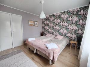 1 dormitorio con 1 cama y papel pintado con motivos florales en Ruma ankanpoikanen, en Pori