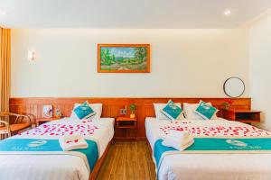 a hotel room with two beds with red flowers on them at Palm Bay Resort Phu Quoc in Phú Quốc