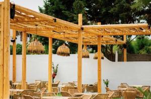 un grupo de mesas y sillas bajo una pérgola de madera en Yiayia Katina’s House en Korinthos