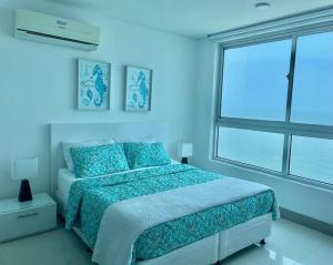 Dormitorio azul con cama y ventana grande en Apartamento 3404 Palmetto Beach Frente a la playa, en Cartagena de Indias