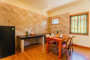 a kitchen with a wooden table and a black refrigerator at Palm Bay Resort Phu Quoc in Phú Quốc