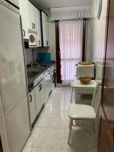 een keuken met witte apparatuur en een tafel met een stoel bij piso en la playa in Noja