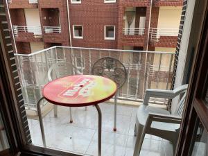 een tafel en 2 stoelen op een balkon met een raam bij piso en la playa in Noja