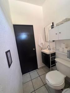 a bathroom with a white toilet and a black door at The Next Door Black and White Studio In Cabo in Cabo San Lucas