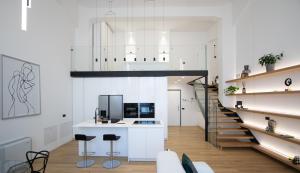 a kitchen with white walls and a staircase with stools at Loft Milano Manifatture2 in Milan