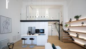 a kitchen with white walls and a staircase with stools at Loft Milano Manifatture 2 in Milan