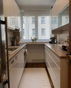 una cucina con armadi bianchi, lavandino e finestre di Great appartment in Vienna a Vienna