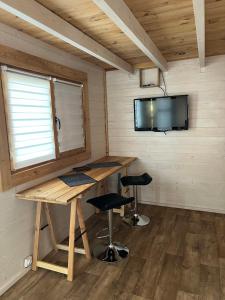 a desk in a room with a tv and stools at Tiny-House Chalet Al måjhinete in Lodève