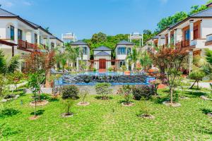 a garden with trees in front of a building at Palm Bay Resort Phu Quoc in Phu Quoc