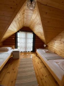 two beds in a wooden room with a window at Ruralna kuća za odmor Marta in Otočac