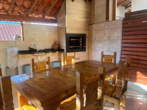 una gran mesa de madera y sillas en la cocina en Chalé em Resort, en Mairinque