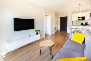 a living room with a couch and a tv on a wall at VacationClub – Sosnowa 4 Apartament 40 in Mielno