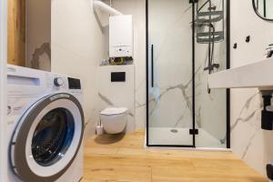lavadero con lavadora y ducha en VacationClub – Sosnowa 4 Apartament 40 en Mielno