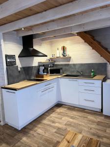 a kitchen with white cabinets and a stove at Tiny-House Chalet Al måjhinete in Lodève