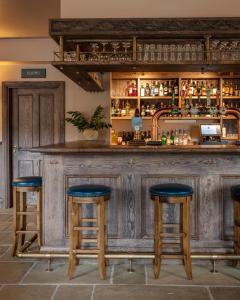 een houten bar met blauwe krukken ervoor bij The Kirkstyle Inn & Sportsman Rest in Brampton